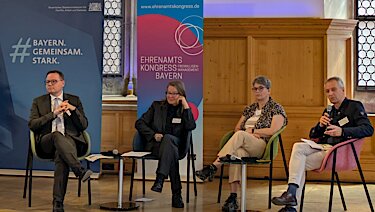Die Teilnehmenden des Podiums sitzen auf der Bühne. Die Teilnehmenden des Podiums sitzen auf der Bühne.